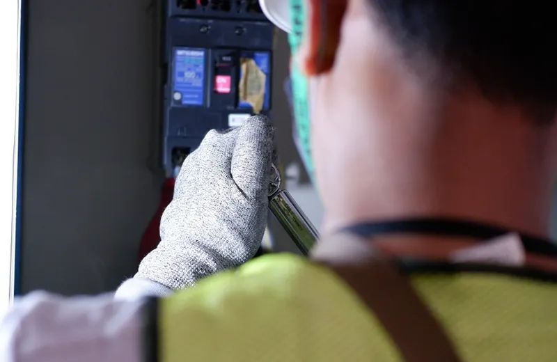 Açıq avtomat qutusunun içində əlcəklə işləyən elektrik