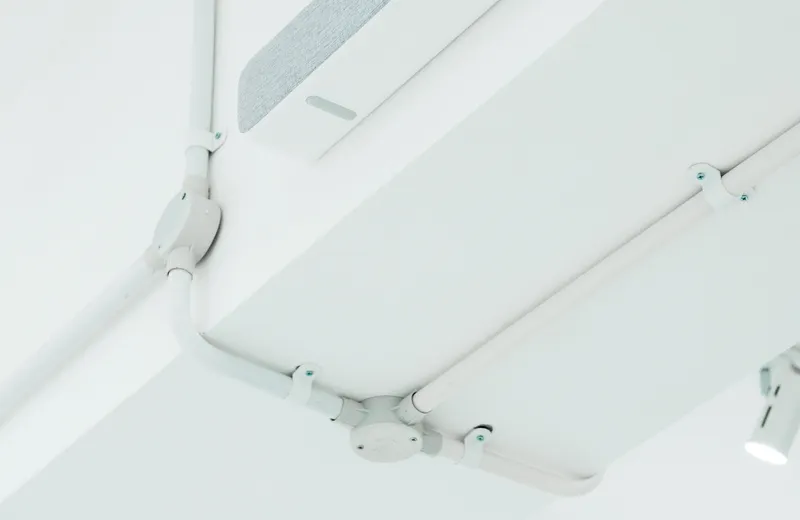 Sənaye tavanı boyunca çəkilmiş açıq boru və kabel kanalları